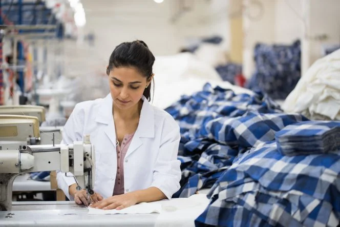 Skilled young tailor sewing on machine